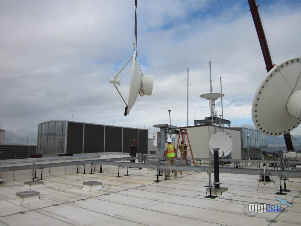Crew installing satellite antennas by crane on a rooftop